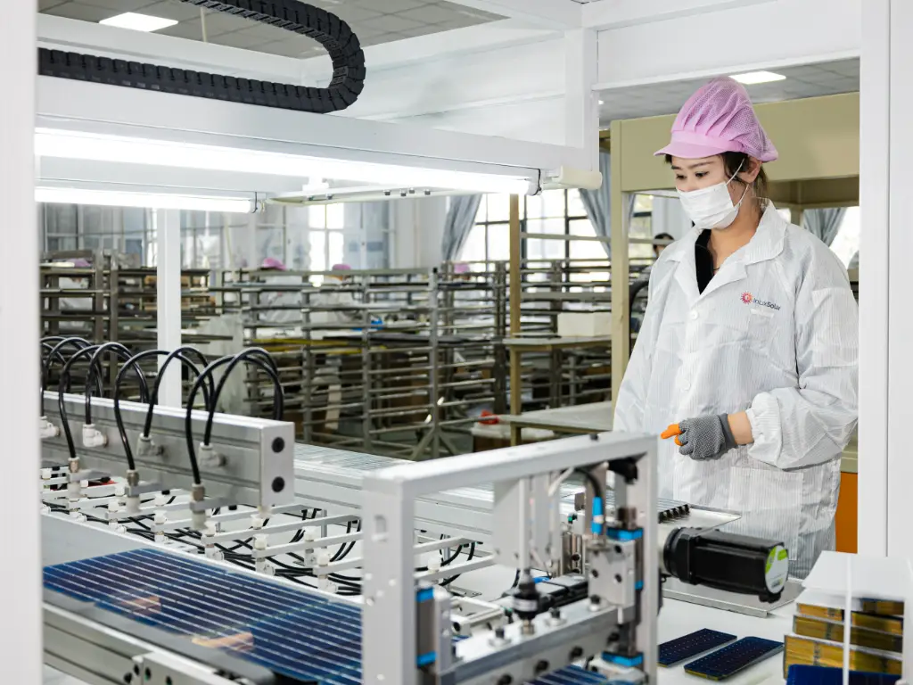 An automated production line for solar panels, with workers in lab coats operating the line