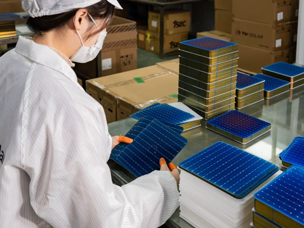 An employee stands in the battery cell raw material area, holding a battery cell to check whether it is of qualified quality.